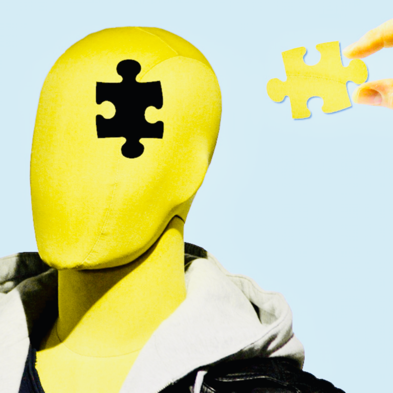 Das Bild zeigt einen gelben Kopf einer gesichtslosen Schaufensterpuppe. Mitten im Kopf fehlt ein Puzzleteil. Ein passendes Teil wird rechts davon von zwei Fingern gehalten.